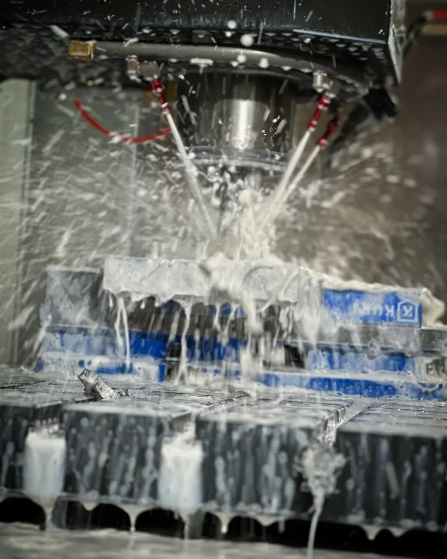 A CNC machine cutting a metal part under flood coolant at NCX Concepts in Charlotte, NC.
