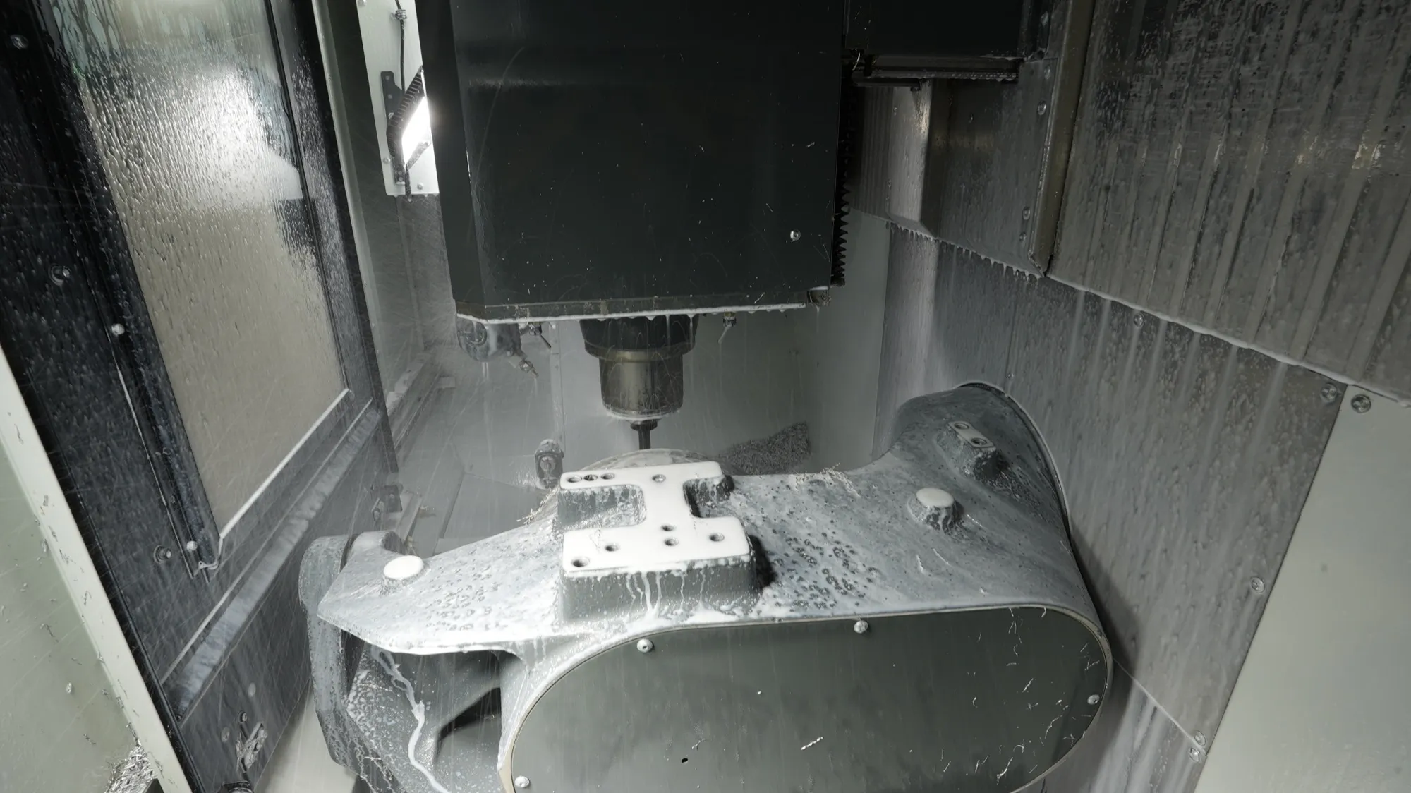 A large part covered in coolant being machined on a 5-axis CNC at NCX Concepts in Charlotte, NC.
