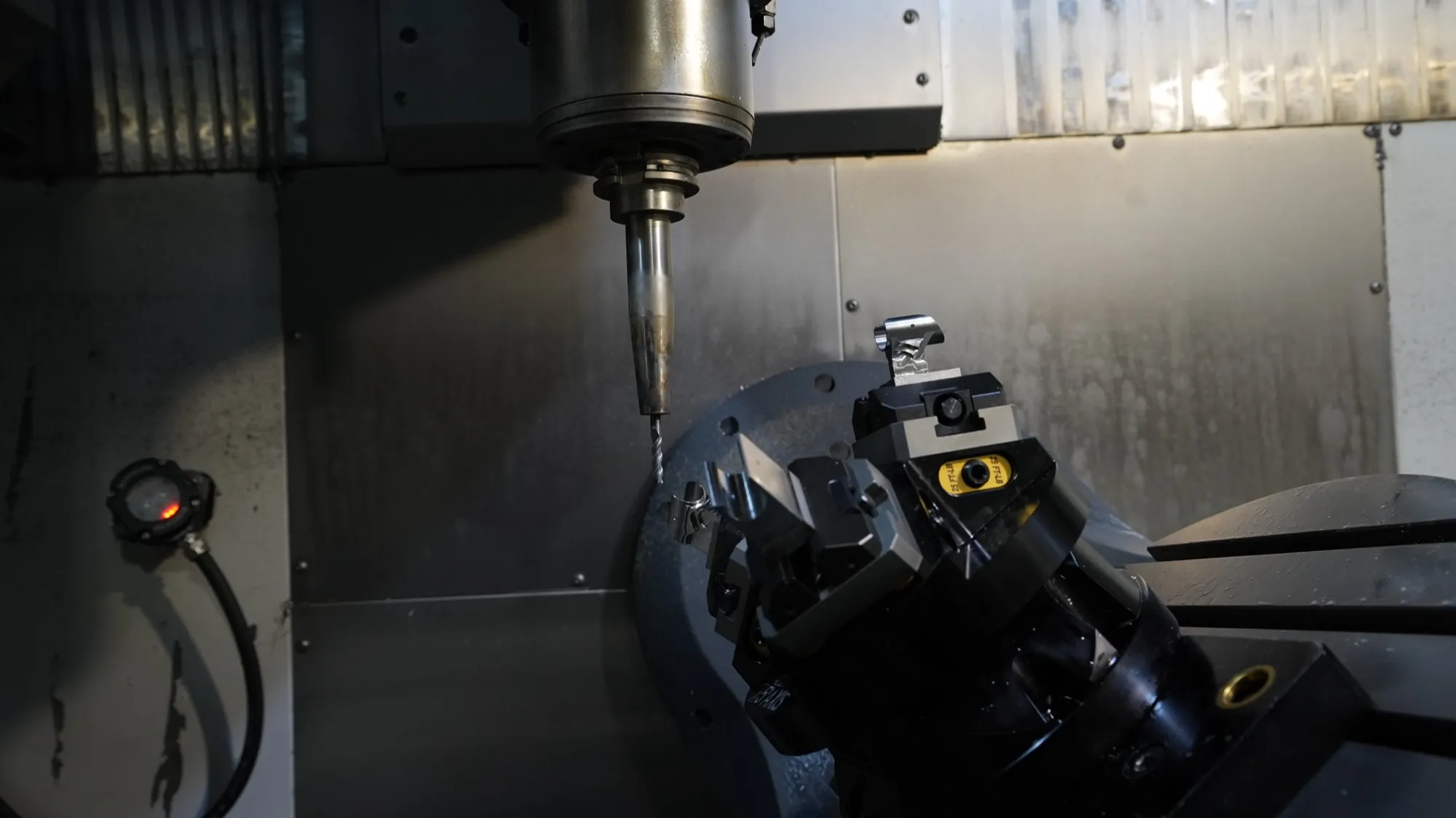 A 5-axis trunnion with a self-centering vise tilted toward the spindle inside a CNC machine at NCX Concepts.